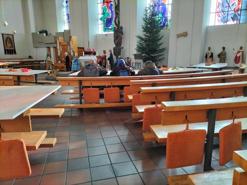 Menschen an den gedeckten Weihnachttischen in St. Peter, Aachen.
