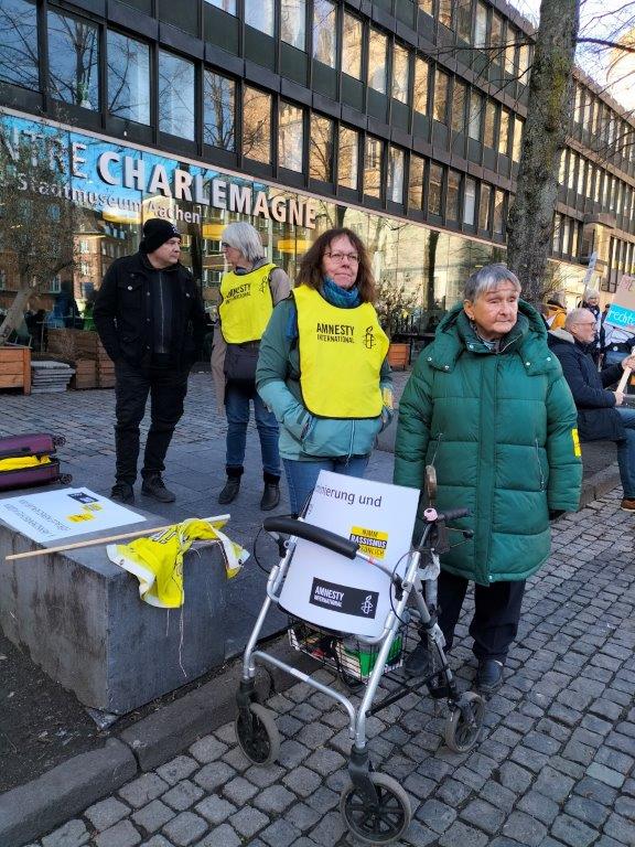 Menschen mit Amnesty-Leibchen und Schildern bei einer Demo vor dem Centre Charlemagne auf dem Aachener Katschhof