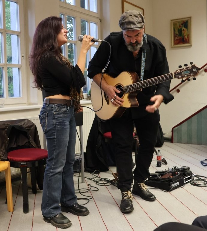 Eine Frau singt, ein Mann spielt dazu Gitarre.