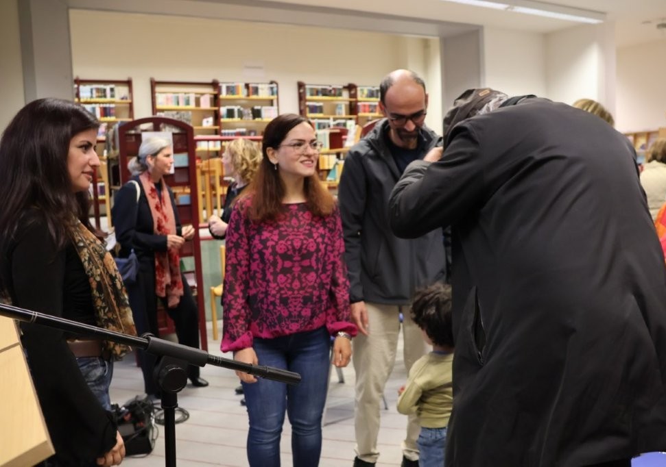 Mehrere Personen stehen zusammen und unterhalten sich in einer Bibliothek.