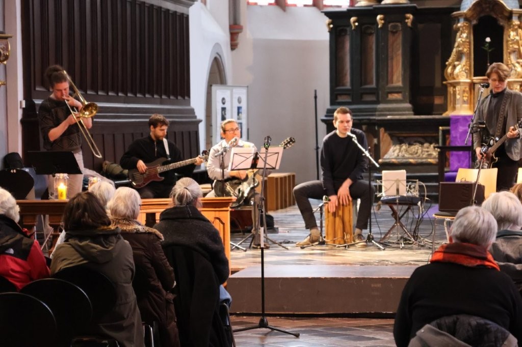 Blick vom Publikum in den Altarraum der Citykirche, dort spielt eine Band mit unterschiedlichen Instrumenten.