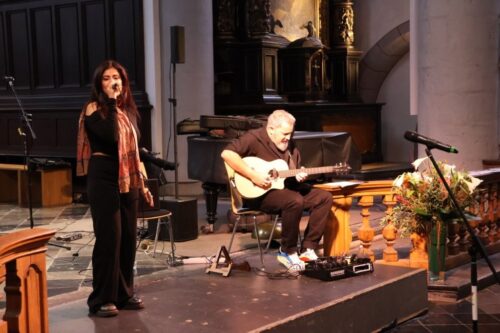 Eine Sängerin singt im Altarraum der Citykirche und wird von einem Gitarristen begleitet.