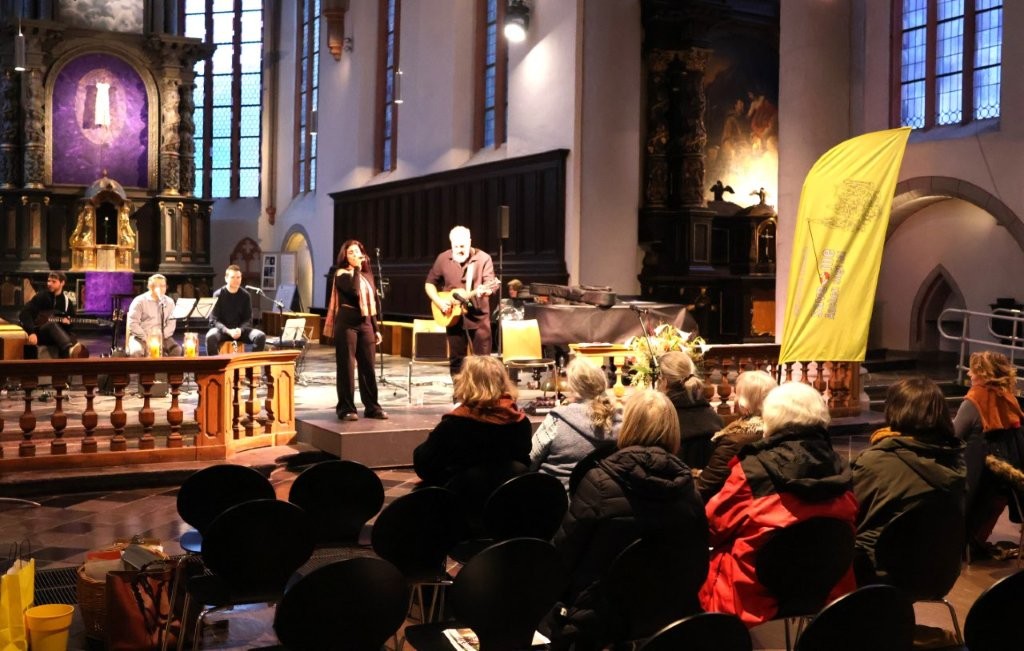 Blick über das Publikum in der Citykirche zum Altarraum. Dort spielt eine Band und es wird gesungen.